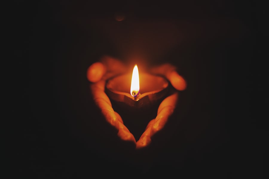 candle alight in praying hands